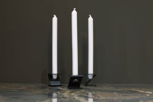 Drie witte kaarsen in minimalistische, witte houder op een glanzende marmeren tafel. Perfect voor een moderne, elegante sfeer in woon- of feestruimte.