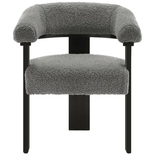 Grijze, fluweelachtige fauteuil met ronde armleuningen en zwarte metalen poten, geschikt voor moderne woonkamer of lounge. Zacht, textuurrijk materiaal voor comfort en stijl.