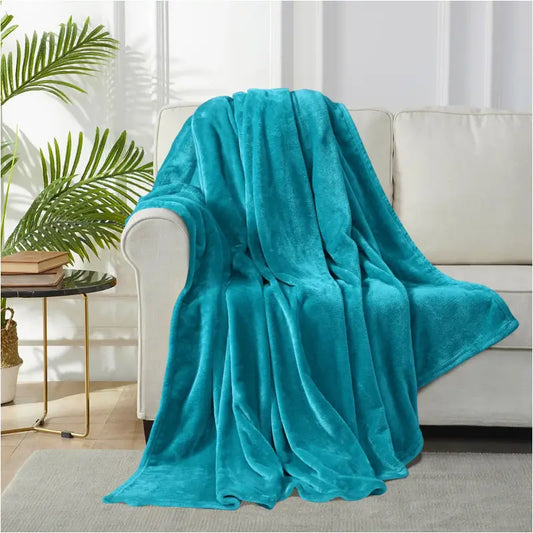 Een zacht, turkoois fluweeldeken, opgevouwen in nette lagen, met een fluweelachtige textuur. Perfect voor comfortabele slaap en warmte in de woonkamer of slaapkamer.