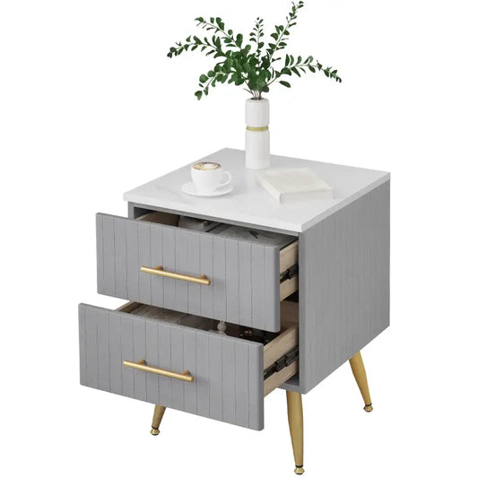 Grijze nachtkastje met witte bovenkant en gouden handgrepen, voorzien van gestikt leer en elegante poten, ideaal voor moderne slaapkamerdecoratie.