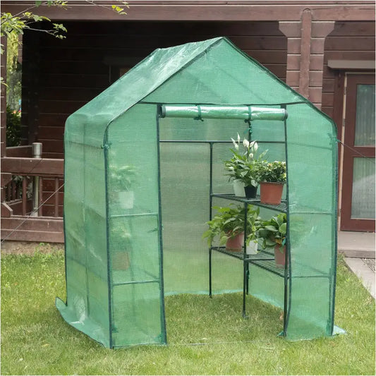 Een witte, mesh-gekleurde tuinserre met groene metalen frame staat op een groen gazon. Binnen staan potten met groene planten en een rol zonbescherming, geschikt voor tuinbouw en groeikamer.