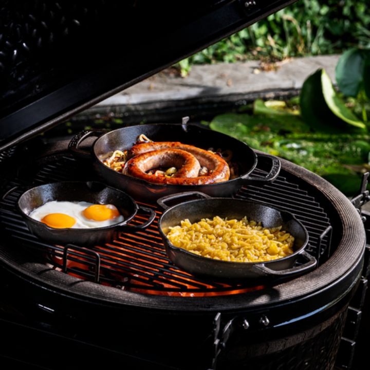 Zware, zwarte gietijzeren koekenpan met twee handvatten, geschikt voor grillen en bakken. Robuust ontwerp voor hoge hitte en langdurig gebruik in de keuken.