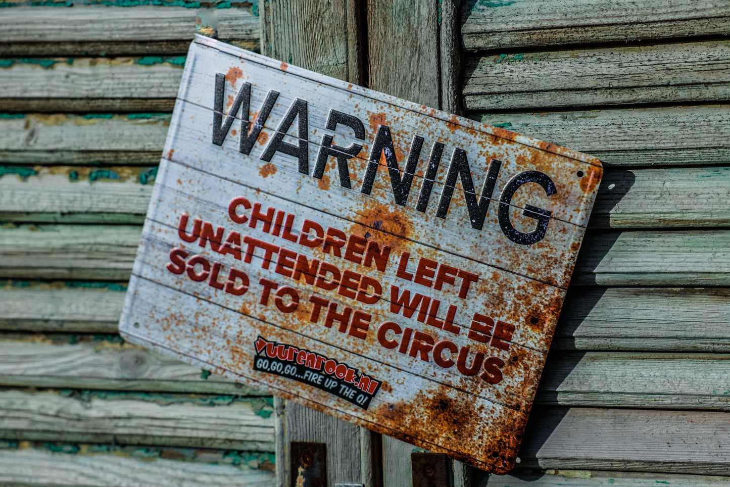 Rustieke waarschuwingsbord met 'WARNING' in zwart en 'CHILDREN LEFT UNATTENDED WILL BE SOLD TO THE CIRCUS' in rood, op verweerd metaal met roestpatronen. Perfect voor decoratie in circus- of speelkamerthema’s.