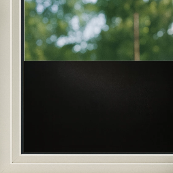 Zwart glasfolie op een wit raamkozijn, zacht mat en volledig lichtdicht, perfect voor privacy en zonbescherming in woon- of kantoorruimtes.