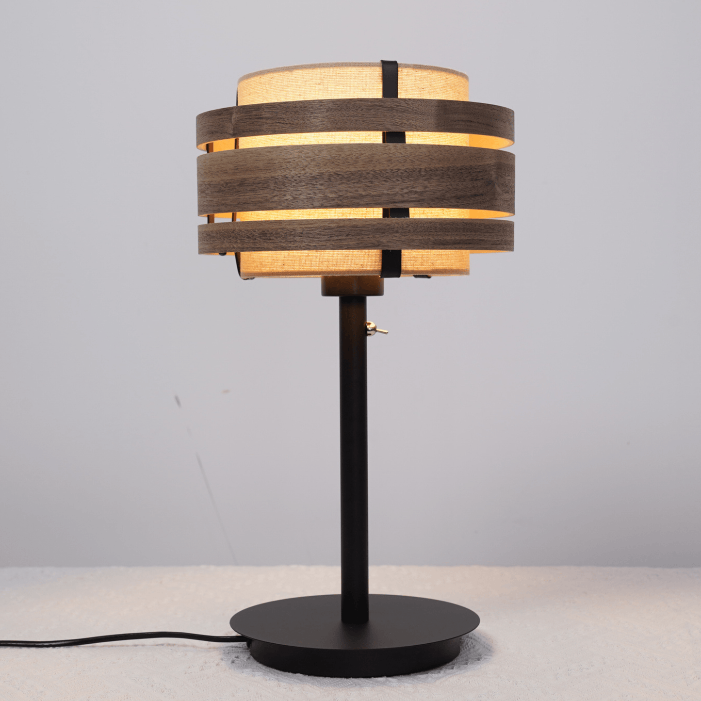 Een moderne wandlamp met donker houten ringen en lichtbeige stoffen kap, voor een warme sfeer in woonkamer of slaapkamer. Geschikt voor minimalistische interieurs en als accentverlichting.