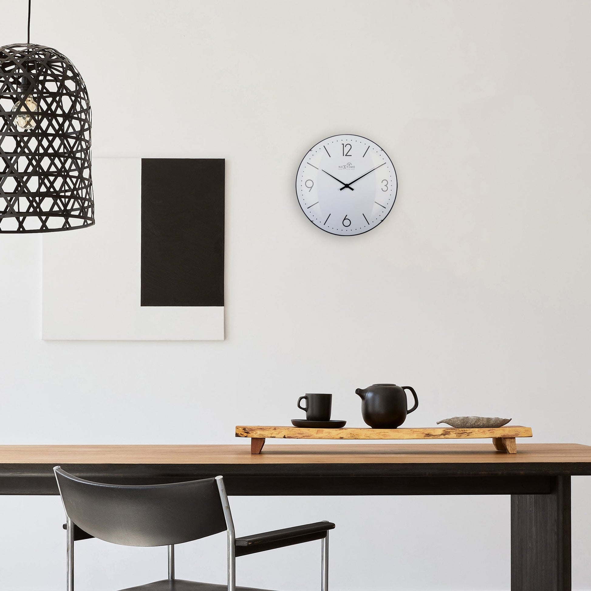 Een moderne, witte wandklok met zwarte wijzers en cijfers, voorzien van radio-afstemming. Geschikt voor minimalistische interieurs en als decoratief element in woon- of kantoorruimtes.