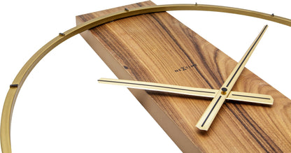 Een minimalistische wandklok met een goudkleurige metalen ring en een houten paneel met donkerbruine, gestreepte textuur. De dunne wijzers en het merk 'NEXTIME' zijn zichtbaar; ideaal voor moderne interieurs en woonkamerdecoratie.