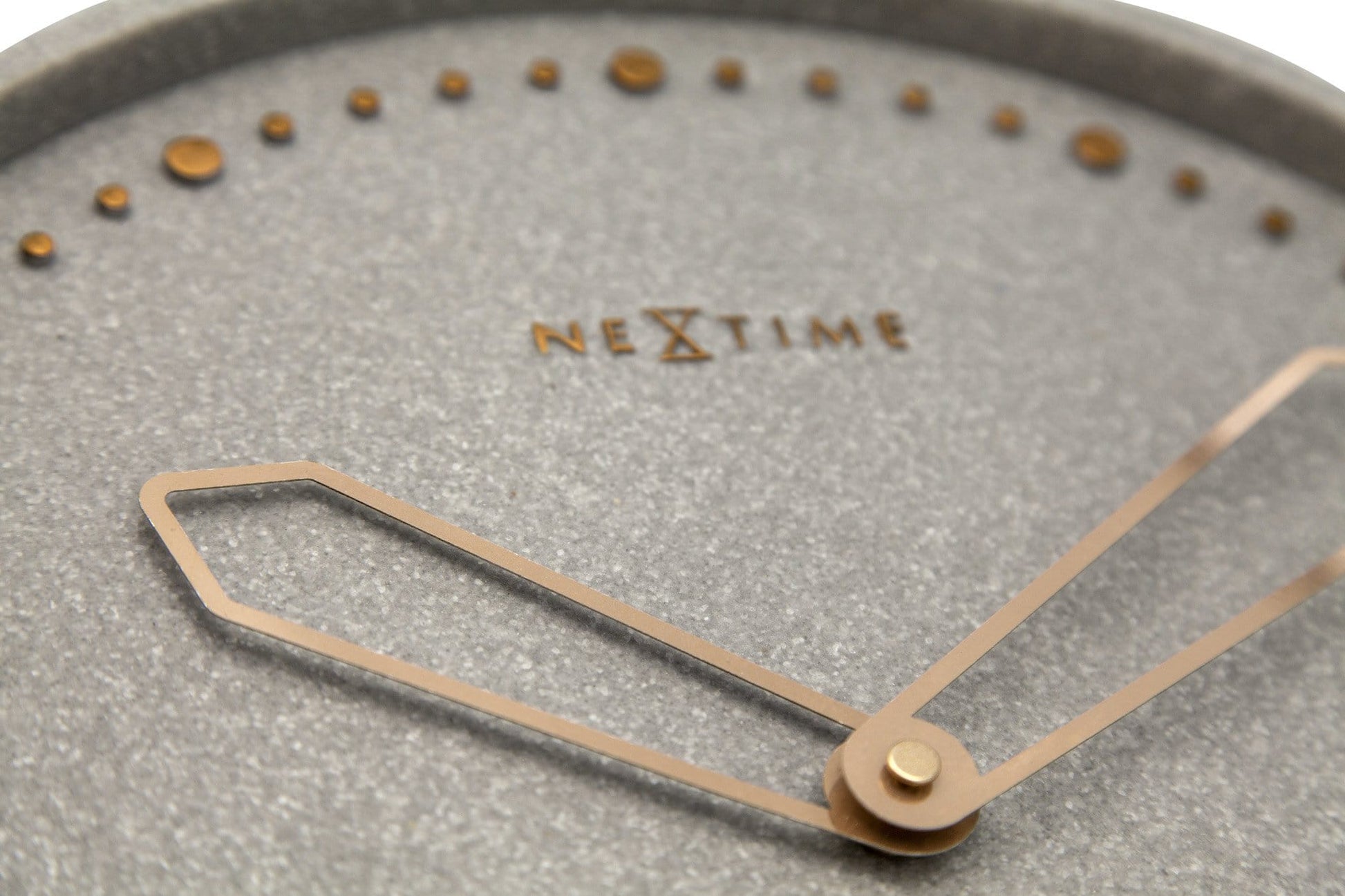 Een moderne wandklok van Nextime met een grijze, textuurrijke wijzerplaat en goudkleurige stippen als uurmarkeringen. De dunne, zilverkleurige wijzers en het minimalistische ontwerp maken deze klok ideaal voor een stijlvolle woonkamer of kantoor.
