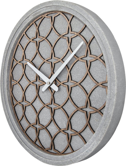 Een moderne wandklok met een grijze betonrand en een houten, geometrisch patroon. Zilveren wijzers en het merk 'NEXTIME' zijn zichtbaar. Geschikt voor minimalistische interieurs en moderne woonkamers.