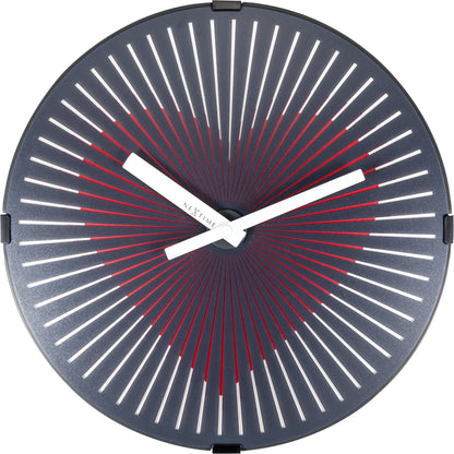 Een moderne wandklok met een donkerblauw oppervlak en rode en witte, zonnestraalvormige wijzers. De minimalistische klok is ideaal voor een stijlvolle woonkamer of kantooromgeving.