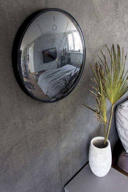 Een minimalistische, zwarte wandklok van Nextime met een mat zwart wijzerplaat en dunne, zilverkleurige wijzers. De klok heeft een moderne, schone esthetiek voor een tijdloze decoratie in woon- of kantoorruimte.