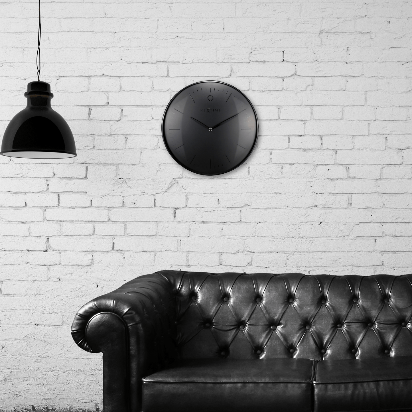 Een minimalistische, zwarte wandklok van Nextime met een mat zwart wijzerplaat en dunne, zilverkleurige wijzers. De klok heeft een moderne, schone uitstraling voor een tijdloze decoratie in woon- of kantoorruimte.
