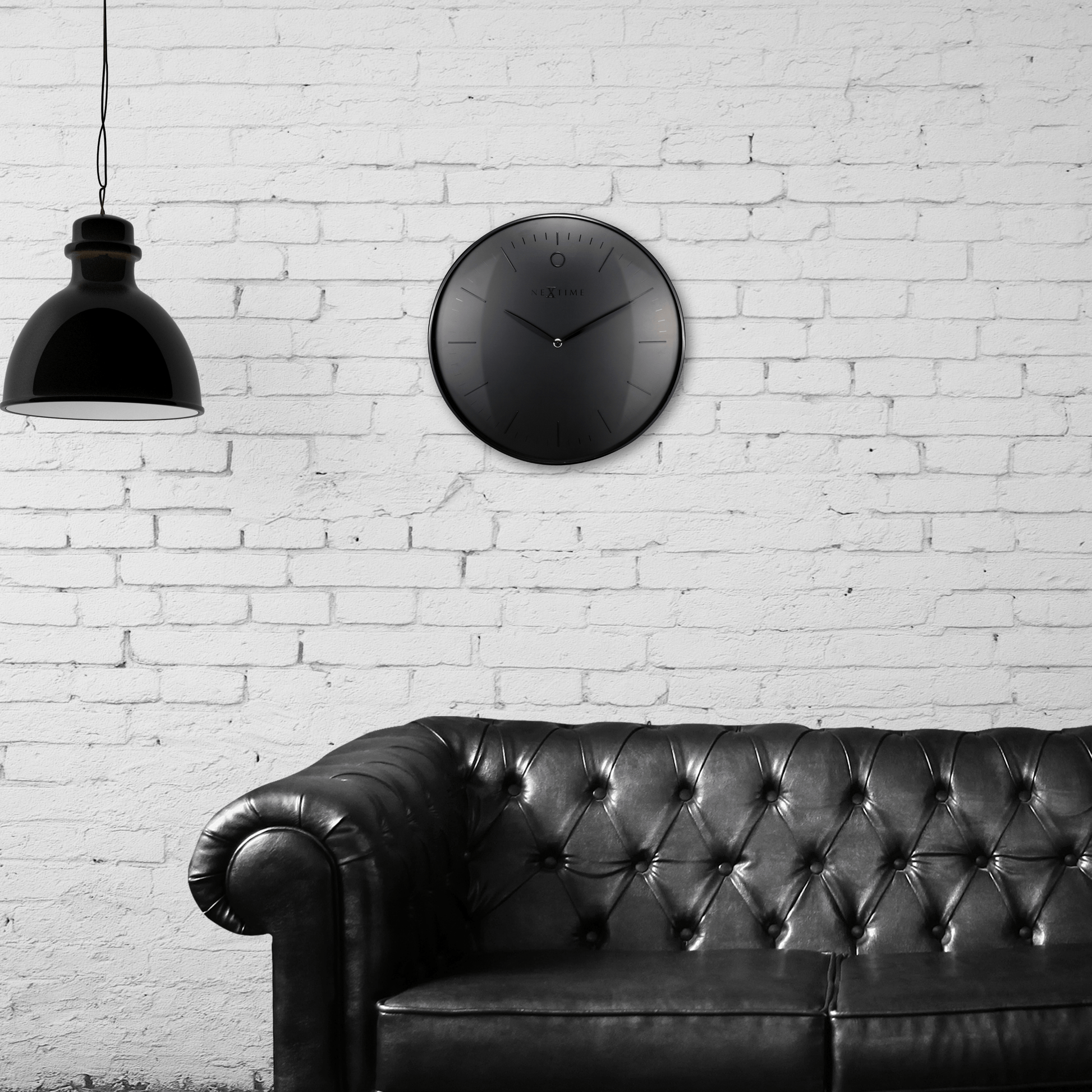 Een minimalistische, zwarte wandklok van Nextime met een mat zwart wijzerplaat en dunne, zilverkleurige wijzers. De klok heeft een moderne, schone uitstraling voor een tijdloze decoratie in woon- of kantoorruimte.