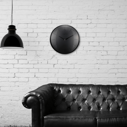 Een minimalistische, zwarte wandklok van Nextime met een mat zwart wijzerplaat en dunne, zilverkleurige wijzers. De klok heeft een moderne, schone uitstraling voor een tijdloze decoratie in woon- of kantoorruimte.
