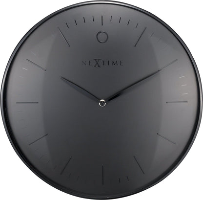 Een minimalistische, zwarte wandklok van Nextime met een mat zwart wijzerplaat en dunne, zilverkleurige wijzers. De klok heeft een moderne, schone esthetiek geschikt voor een stijlvolle woonkamer of kantoorruimte.