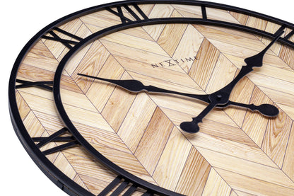 Een ronde wandklok met houten chevronpatroon en zwarte Romeinse cijfers. Zichtbaar merk 'NEXTIME' en elegante wijzers voor moderne interieurs. Perfect voor woonkamer of kantoordecoratie.