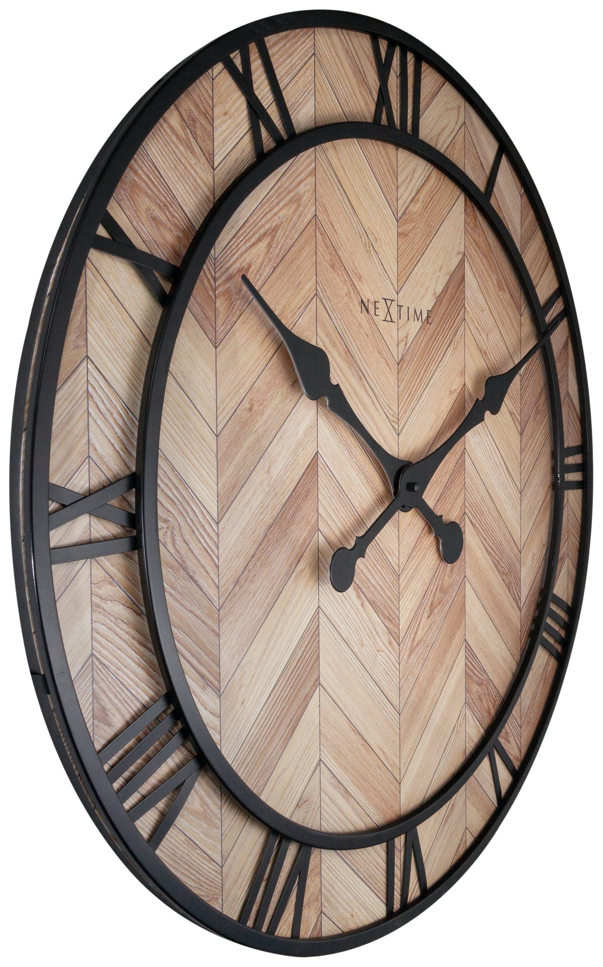 Een ronde wandklok met houten chevronpatroon en zwarte Romeinse cijfers. Zichtbaar merk 'NEXTIME' en elegante wijzers voor moderne interieurdecoratie.