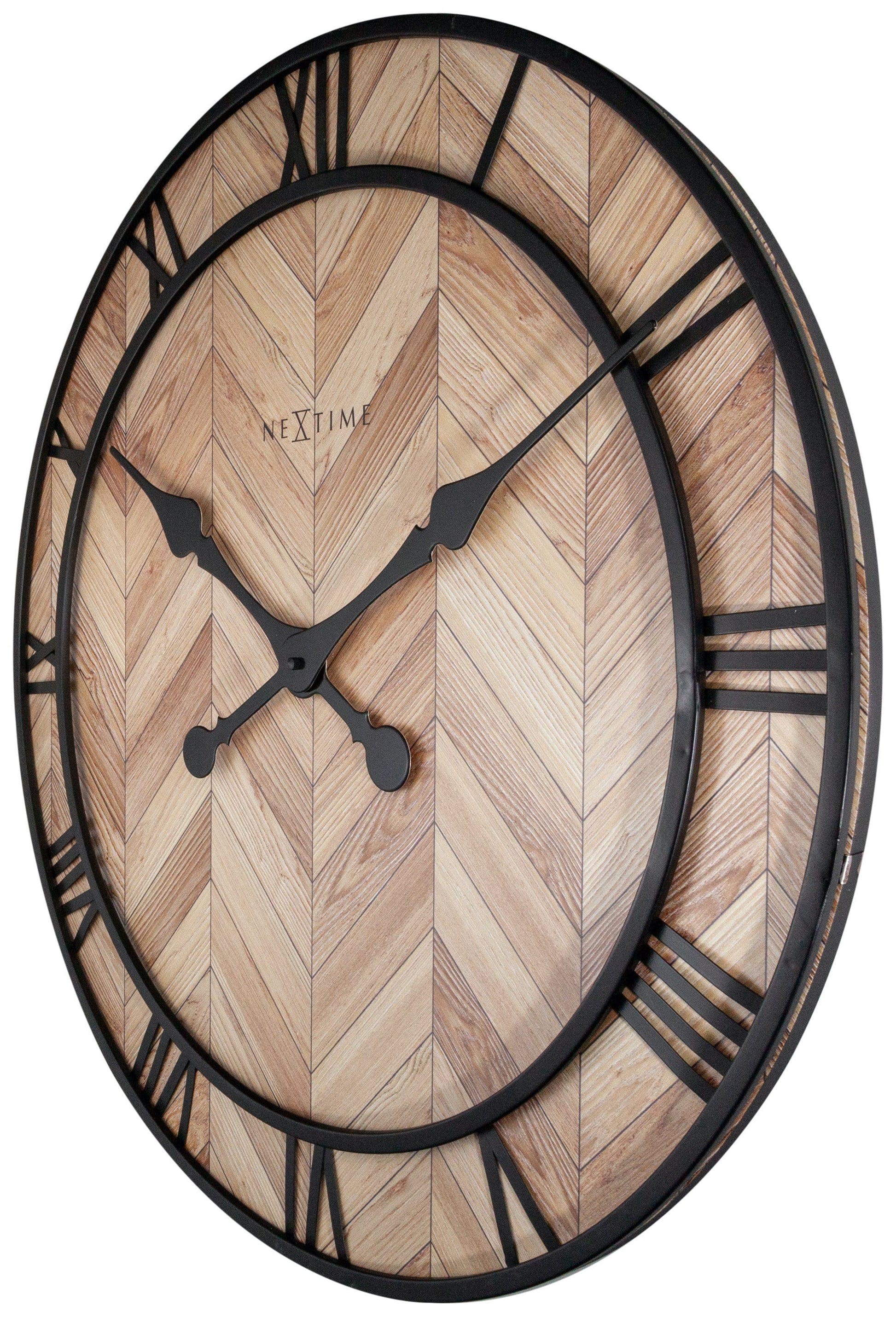 Een ronde wandklok met houten chevronpatroon en zwarte Romeinse cijfers. Zichtbare merknaam ‘NEXTIME’ en elegante wijzers voor moderne interieurstijl. Perfect voor woonkamer of slaapkamer.