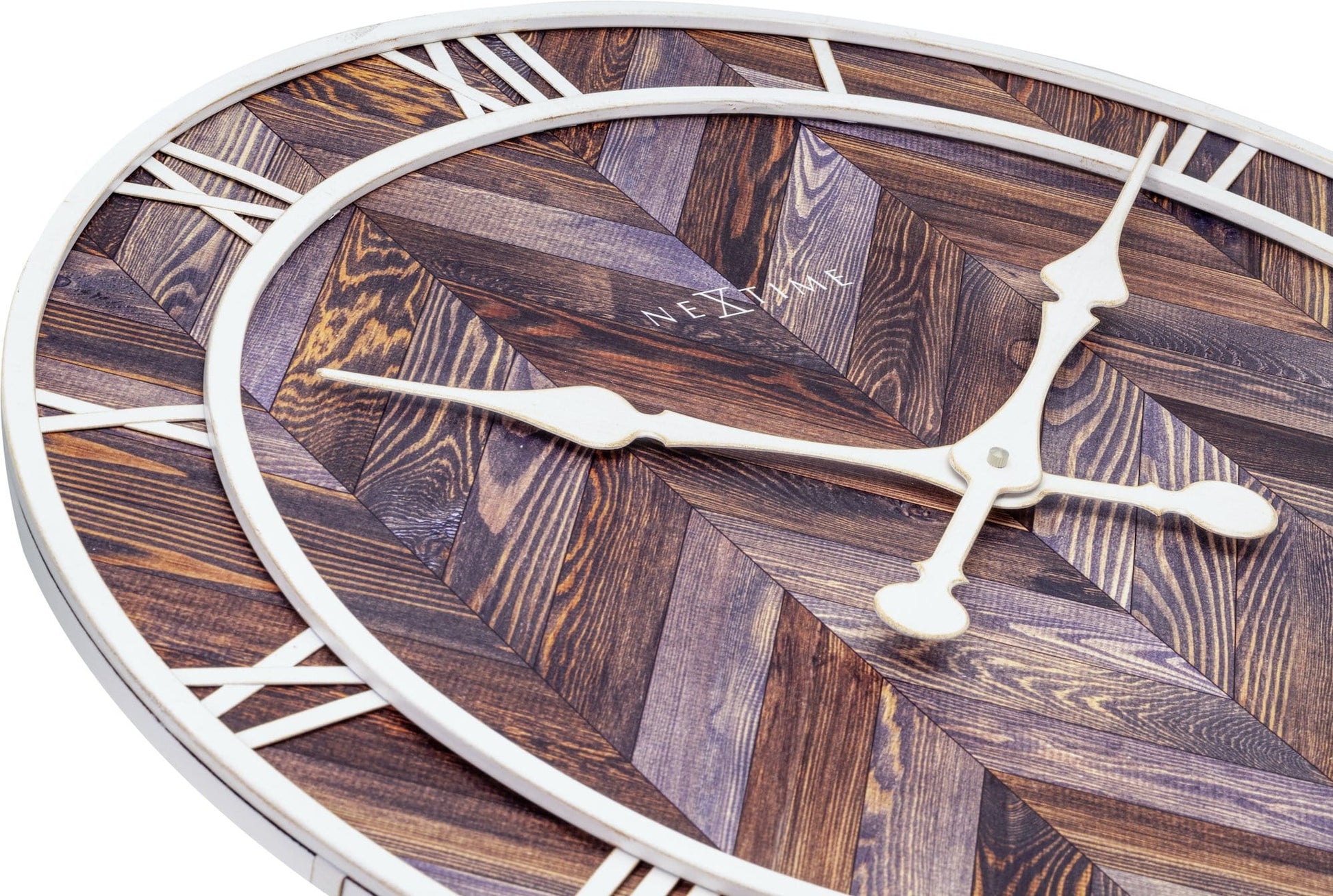 Een ronde wandklok met houten chevronpatroon en witte Romeinse cijfers. De witte wijzers en 'NEXTIME'-merknaam zijn duidelijk zichtbaar. Perfect voor een moderne woonkamer of kantoordecoratie.