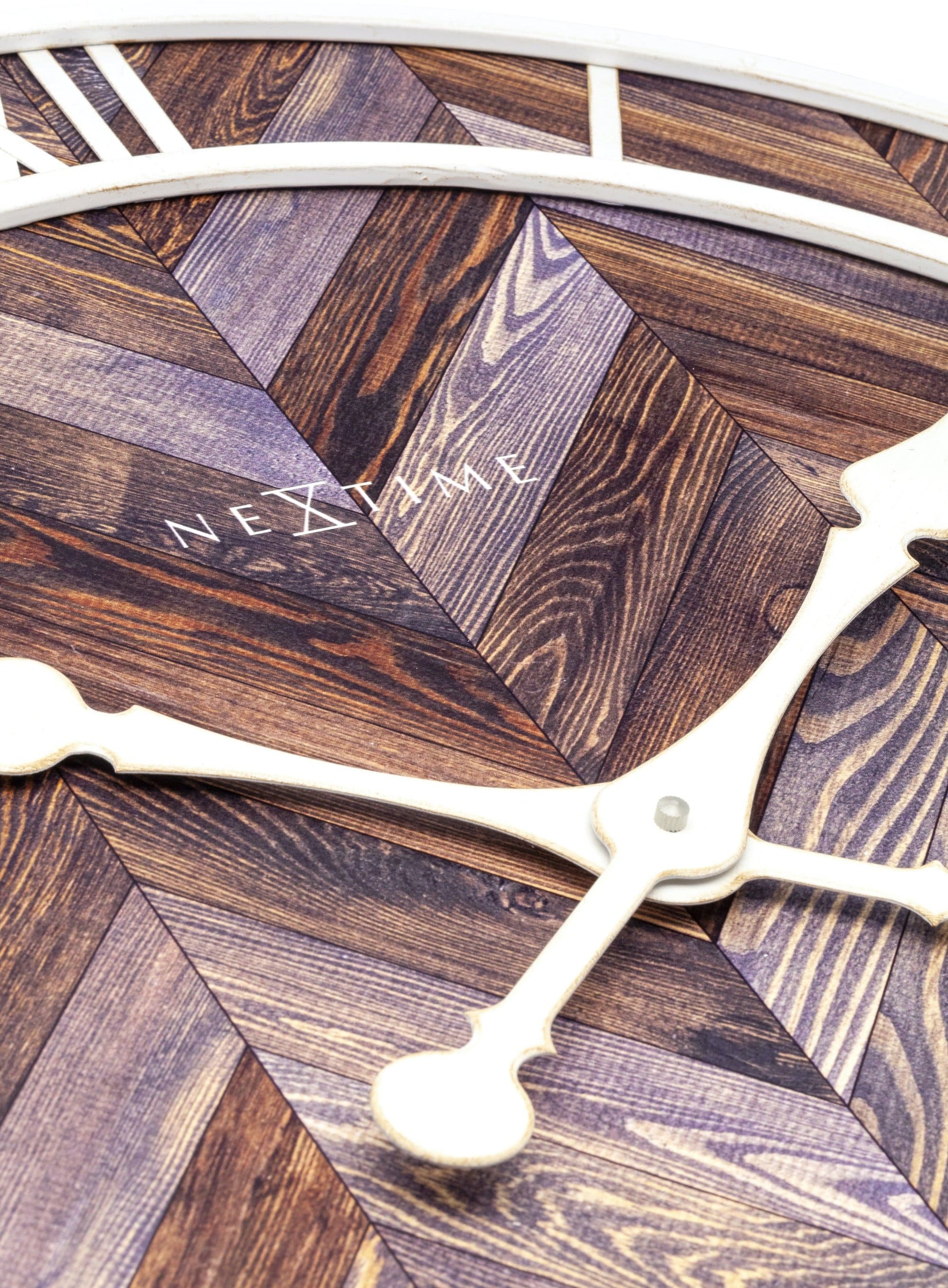 Een ronde wandklok met houten chevronpatroon en witte Romeinse cijfers. De witte wijzers en 'NEXTIME' merknaam zijn duidelijk zichtbaar. Ideaal voor een moderne woonkamer of kantoordecoratie.