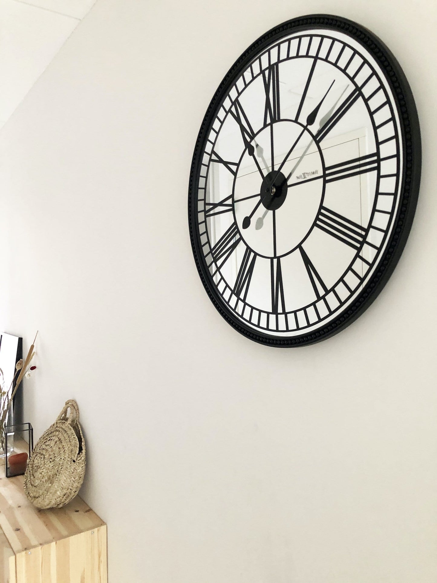 Een klassieke wandklok met zwart metalen kader en witte wijzerplaat met Romeinse cijfers. De klok heeft een elegante, klassieke stijl geschikt voor woonkamer of kantoor.