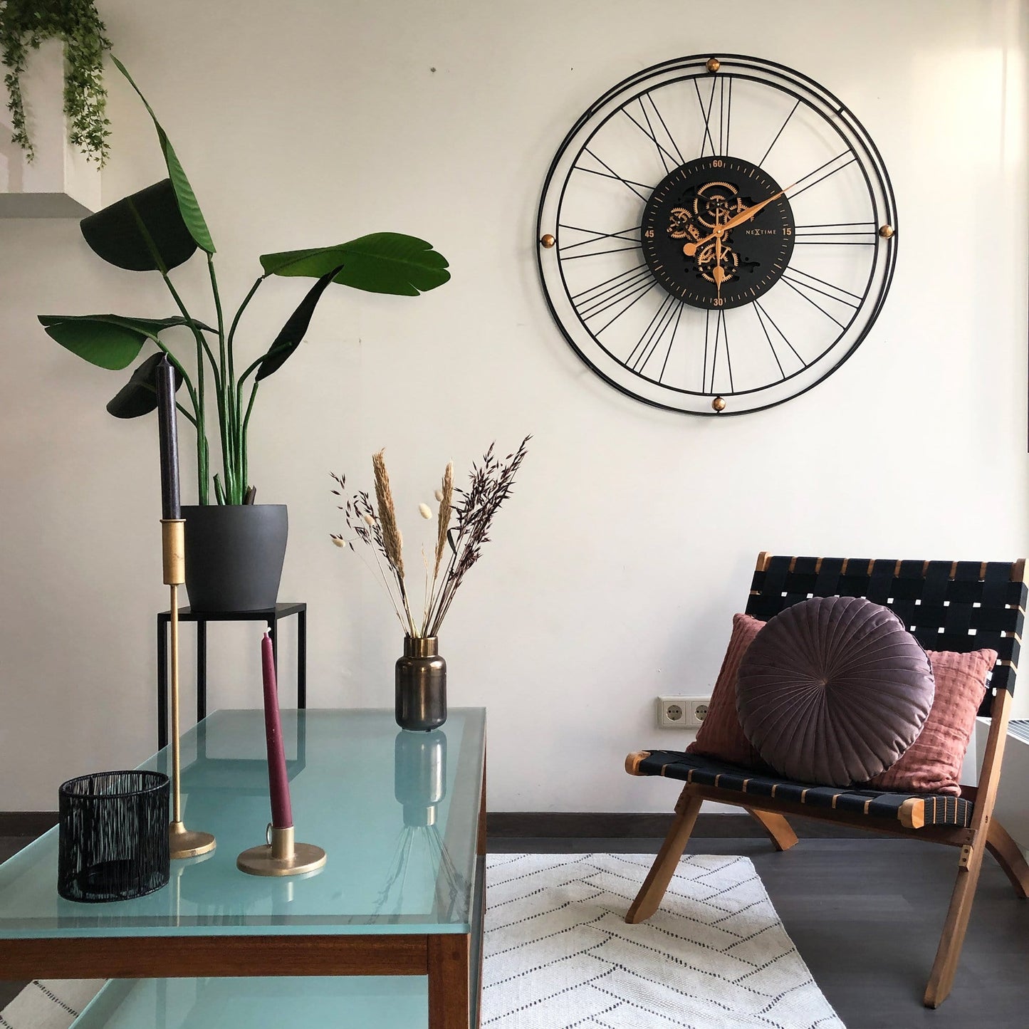 Een industriële wandklok met zwart metaalframe en zichtbare goudkleurige tandwielen. De wijzerplaat toont een mechanisch uurwerk, ideaal voor een moderne of loft-woonkamer.
