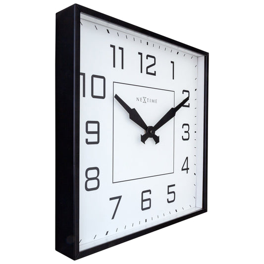 Een minimalistische, zwarte klok met witte wijzerplaat en duidelijke cijfers. De wijzers en het merk 'NEXtime' zijn zwart, geschikt voor moderne interieurs of kantoorruimtes.