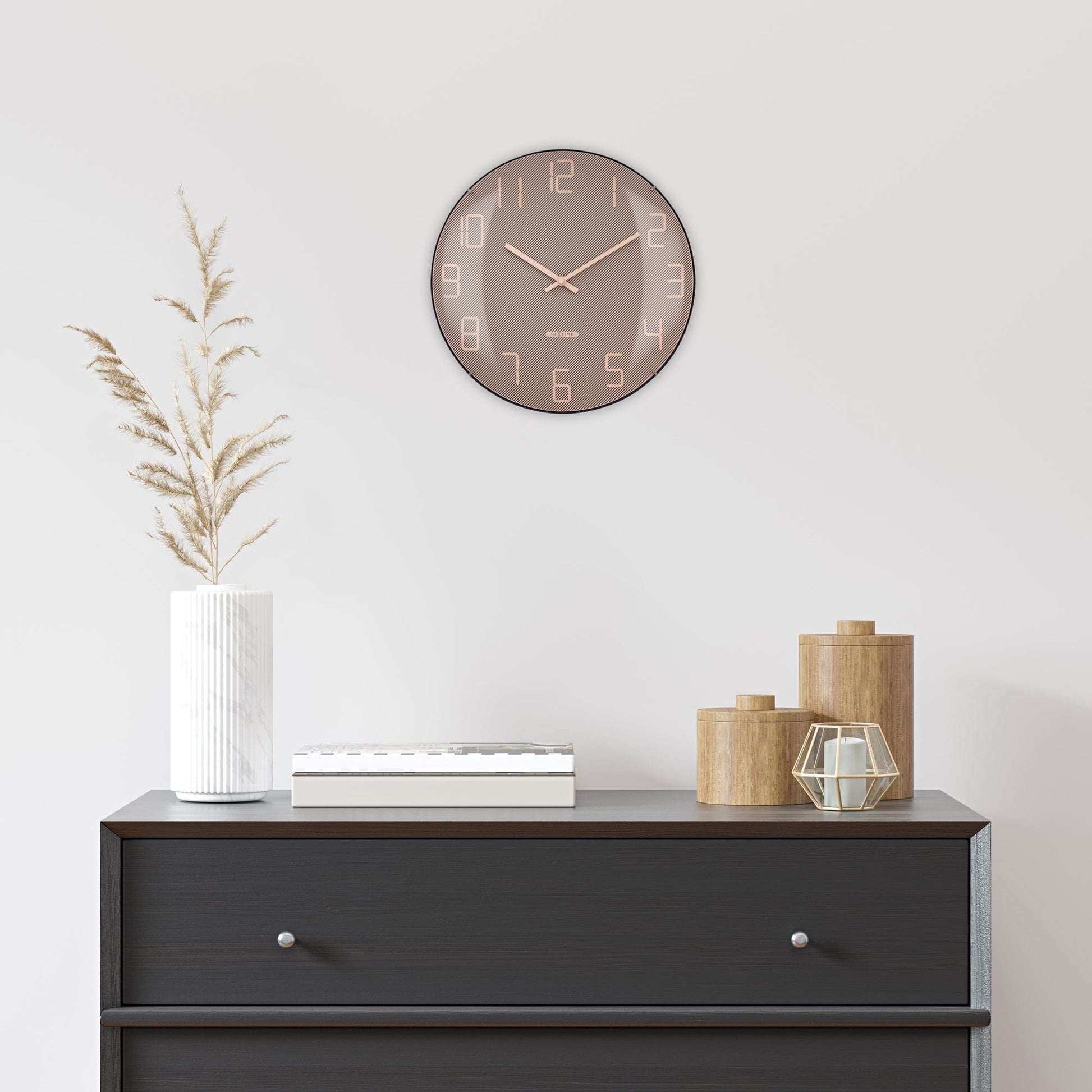 Een moderne wandklok met roze goud kleur en diagonale lijnen, voorzien van witte cijfers en dunne wijzers. Ideaal voor een minimalistische woonkamer of kantoordecoratie.