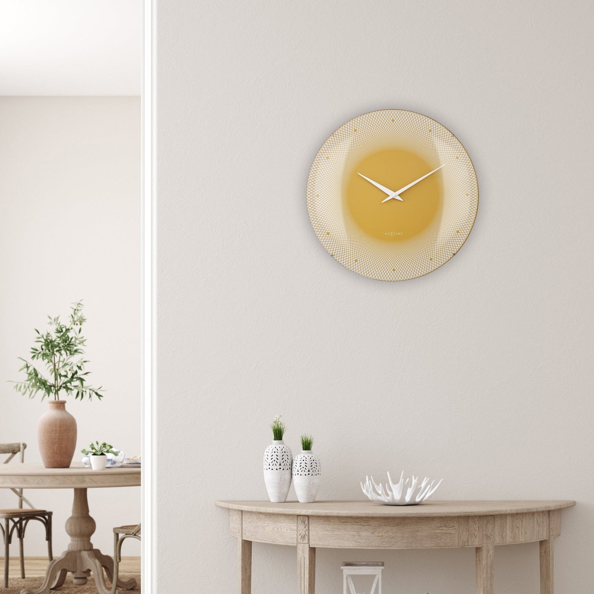 Een moderne wandklok in warme goudkleur met witte wijzers en een geometrisch patroon. Geschikt voor woonkamer of kantoor, met minimalistisch design en het merk NEXtime.