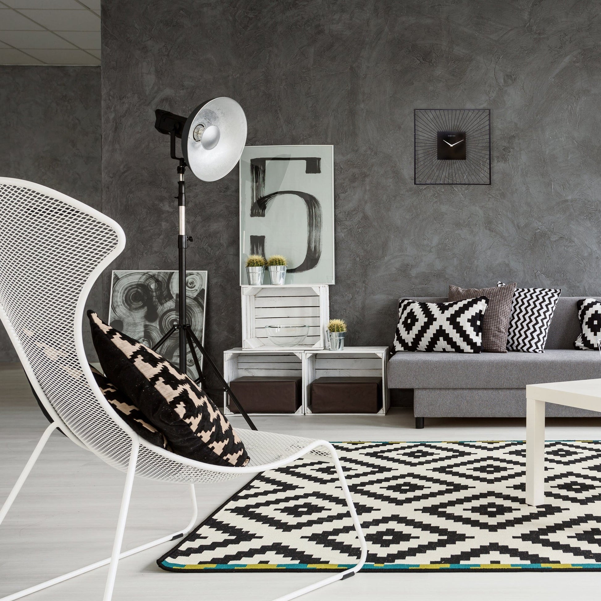 Een moderne, zwarte wandklok met zonnestraalontwerp en zilveren wijzers. Geschikt voor minimalistische interieurs en als decoratief element in woon- of kantoorruimtes.