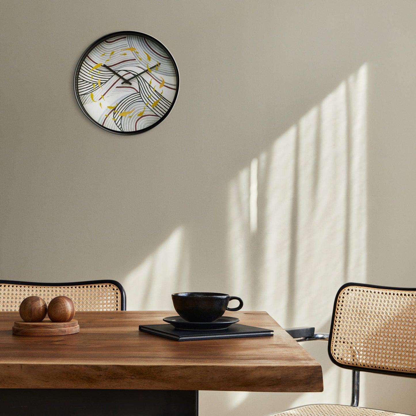 Een ronde wandklok met zwart frame en een abstract ontwerp van golvende lijnen in grijs en paars, versierd met gouden vissen. Ideaal voor moderne interieurs en als decoratief element in woon- of kantoorruimtes.