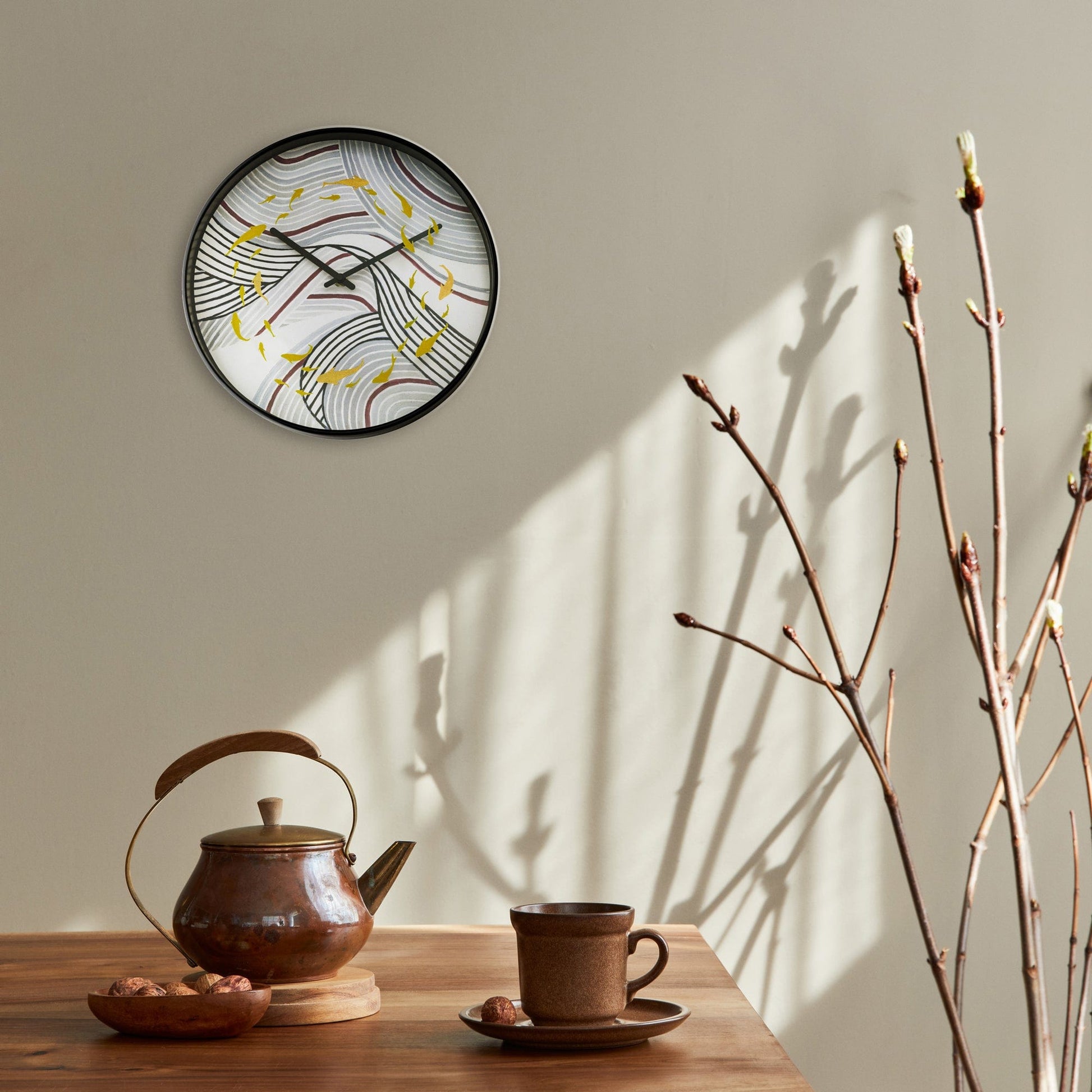 Een ronde wandklok met zwart frame en een abstract ontwerp van golvende lijnen in paars, grijs en wit, versierd met gouden vissen. Perfect voor moderne interieurs en als decoratieve wandklok in woon- of kantoorruimtes.