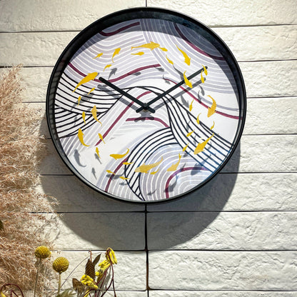 Een ronde wandklok met zwart frame en een kunstwerk van gouden vissen op gestreepte golven. Perfect voor een moderne woonkamer of kantoordecoratie met een artistieke touch.