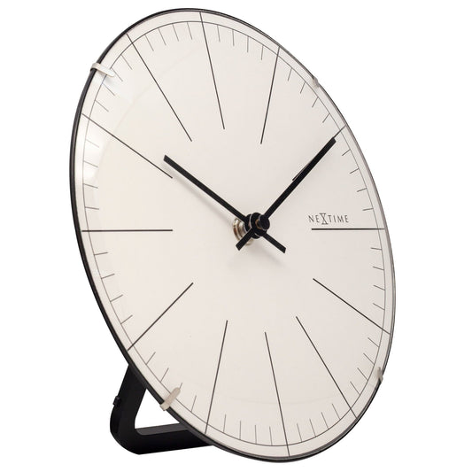 Een minimalistische wandklok met een witte wijzerplaat, zwarte wijzers en een zwart metalen kader. De merknaam 'NEXTIME' is zichtbaar, geschikt voor moderne interieurs en kantoorruimtes.