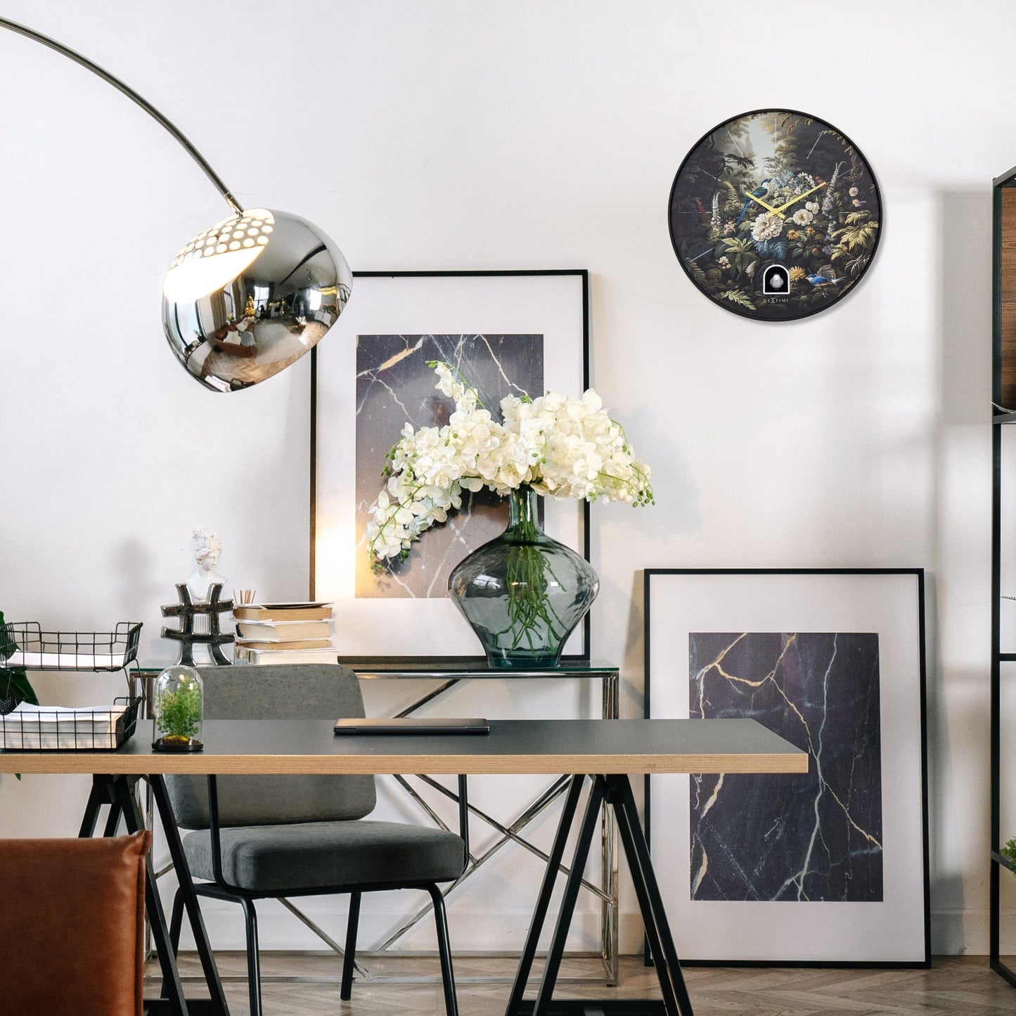 Een ronde wandklok met een donkere, botanische print van bloemen en vogels, voorzien van gele wijzers en een witte vogel in een houten nis. Perfect voor een natuurlijke, decoratieve sfeer in woonkamer of slaapkamer.