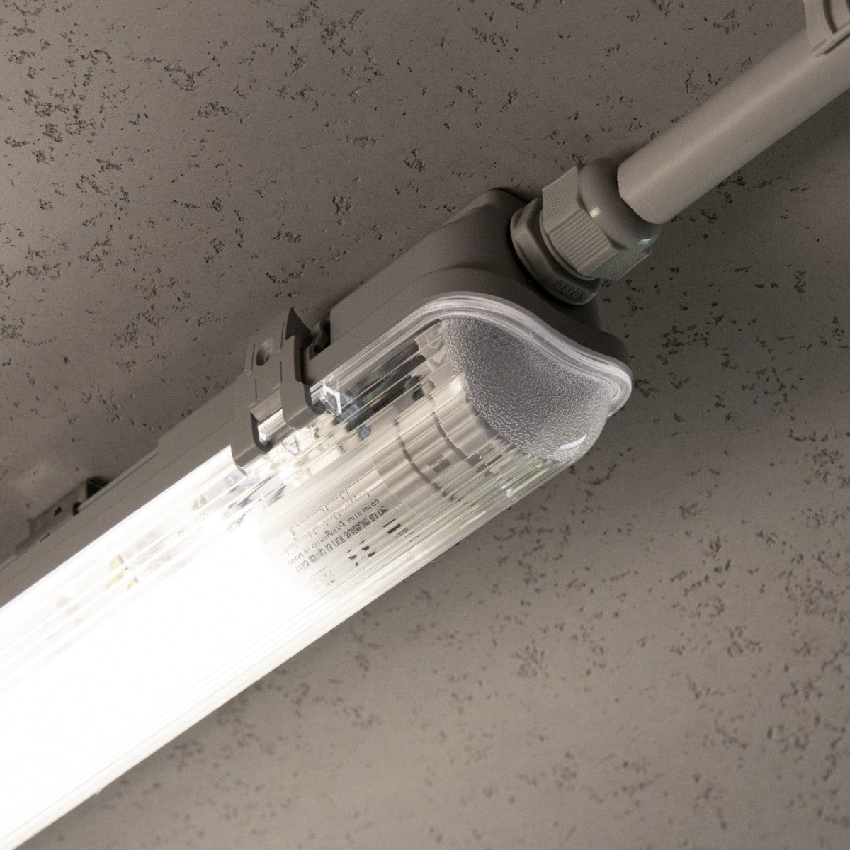 Zilverkleurige LED-balklamp met vier witte aansluitingen, geïntegreerd met vier witte T8 LED-buisverlichting voor energiezuinige verlichting in kantoren en industriële ruimtes.