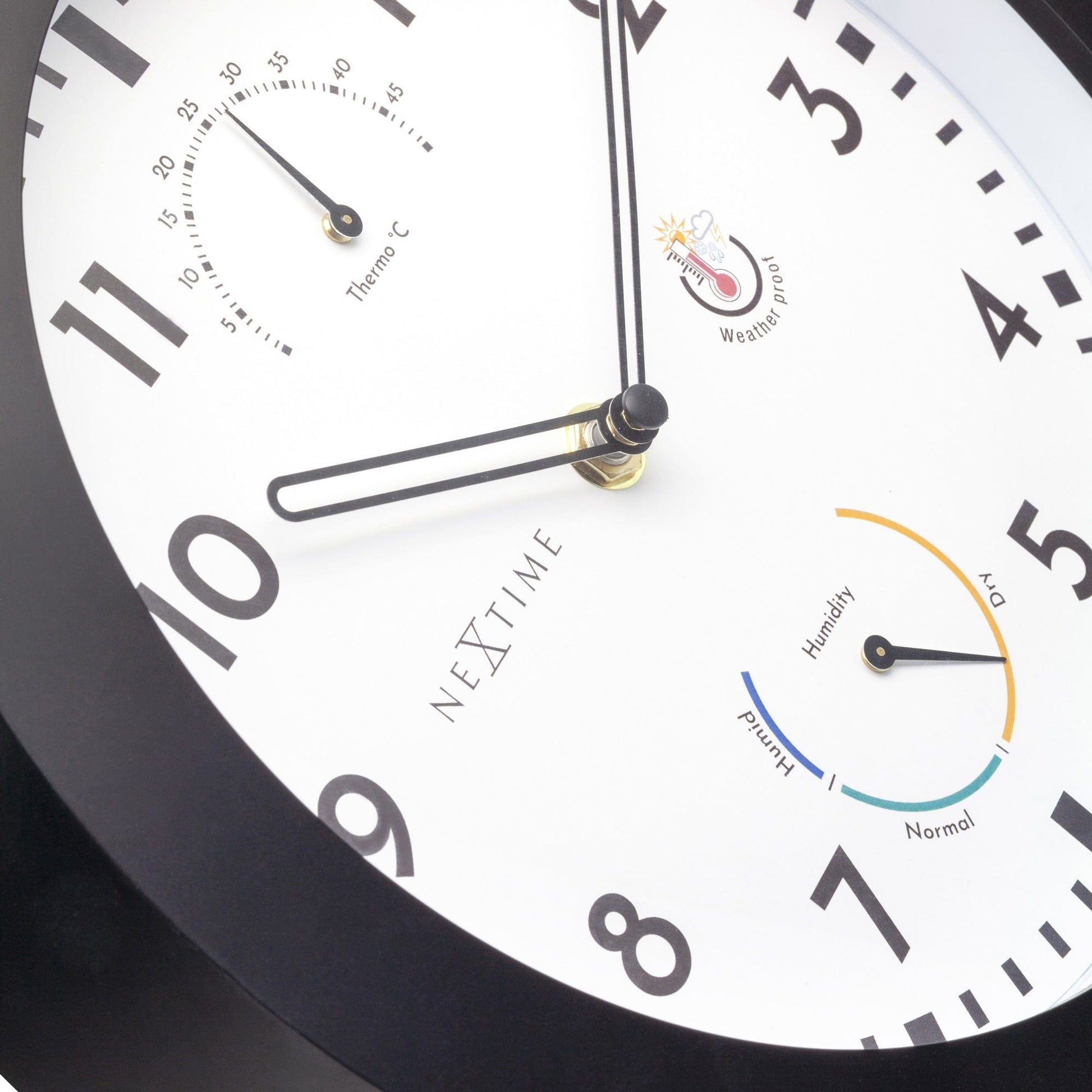 Een zwarte wandklok van Nextime met witte wijzerplaat, grote zwarte cijfers en een thermometer. Inclusief vochtigheidsmeter en weerbestendigheid, ideaal voor huis of kantoor.