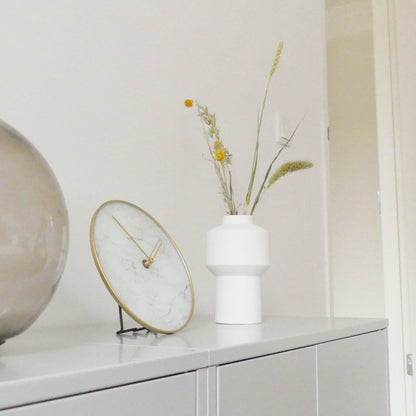 Een elegante wandklok met wit marmeren wijzerplaat en goudkleurige wijzers, omlijst door een goudkleurige metalen rand. Geschikt voor moderne interieurs en kantoorruimtes met minimalistische stijl.