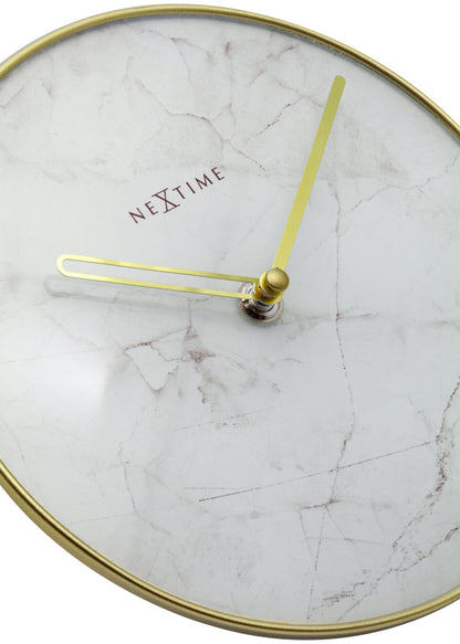 Een ronde wandklok met wit marmeren wijzerplaat en goudkleurige wijzers. De klok heeft een goudkleurige metalen rand en het merk 'NEXTIME' in het midden. Perfect voor moderne interieurs en als decoratief element.