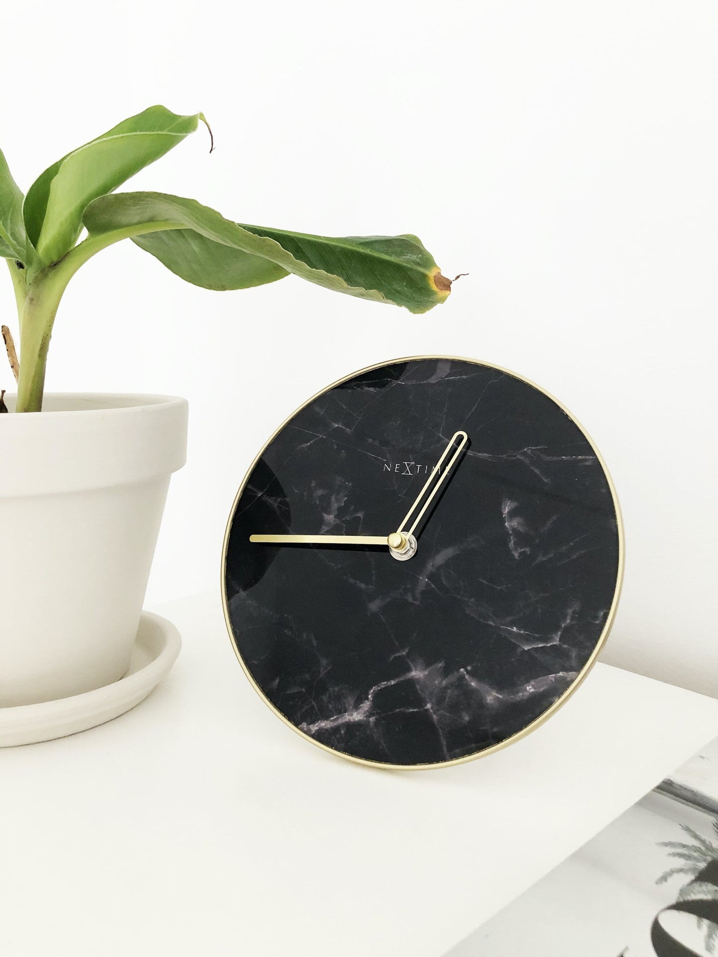 Een elegante wandklok met zwart marmeren wijzerplaat en goudkleurige wijzers. De minimalistische klok is ideaal voor moderne interieurs en past perfect in een woonkamer of kantoor.