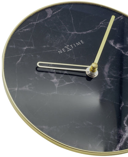 Een elegante wandklok met zwart marmeren wijzerplaat en goudkleurige wijzers. De minimalistische klok heeft een goudkleurige rand en het merk 'NEXTIME' in het midden, ideaal voor moderne interieurs.