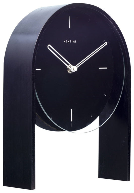 Een minimalistische zwarte wandklok van Nextime met witte wijzers en dunne markeringen, ondersteund door een elegante houten standaard. Perfect voor moderne interieurs en als decoratief element in woon- of kantoorruimtes.