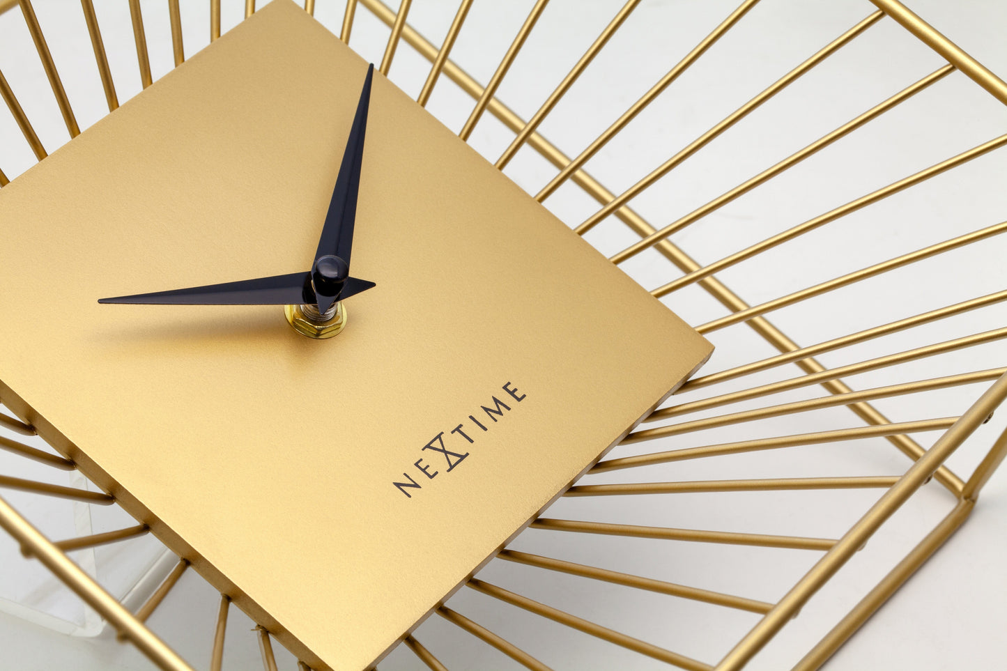 Een goudkleurige wandklok met een minimalistisch ontwerp, een vierkante kast van metaal met zichtbare zonnestralen, en zwarte wijzers. Geschikt voor moderne interieurs en als decoratief element in woon- of kantoorruimtes.