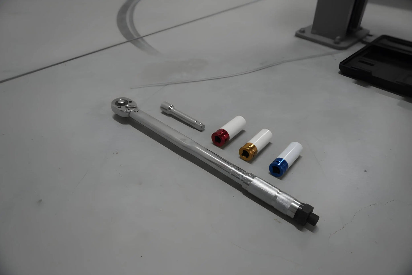 Zilverkleurige schroefspanner met kleurrijke, gestreepte accessoires in een zwarte houder. Geschikt voor precisiewerkzaamheden in de auto- en reparatiewereld.