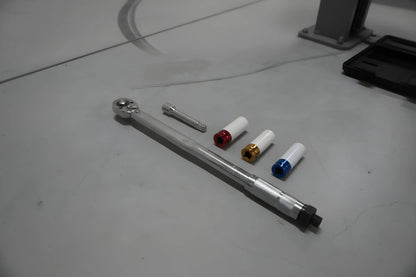 Zilverkleurige schroefspanner met kleurrijke, gestreepte accessoires in een zwarte houder. Geschikt voor precisiewerkzaamheden in de auto- en reparatiewereld.