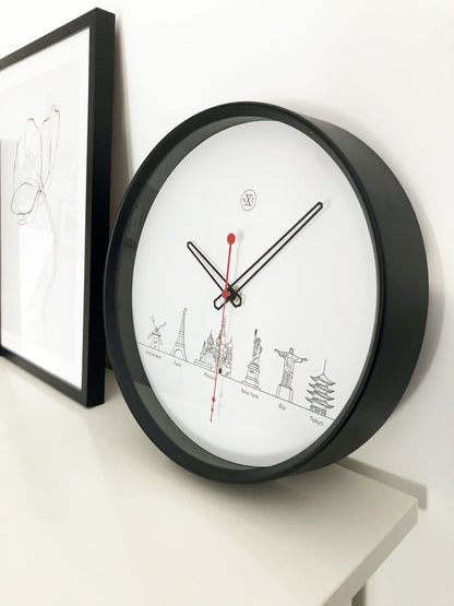Een minimalistische wandklok met zwart kader en wit oppervlak, voorzien van zwart wijzerplaat en rode secondewijzer. De wijzerplaat toont gestileerde wereldstadiconen, ideaal voor een moderne, wereldwijde interieurdecoratie.