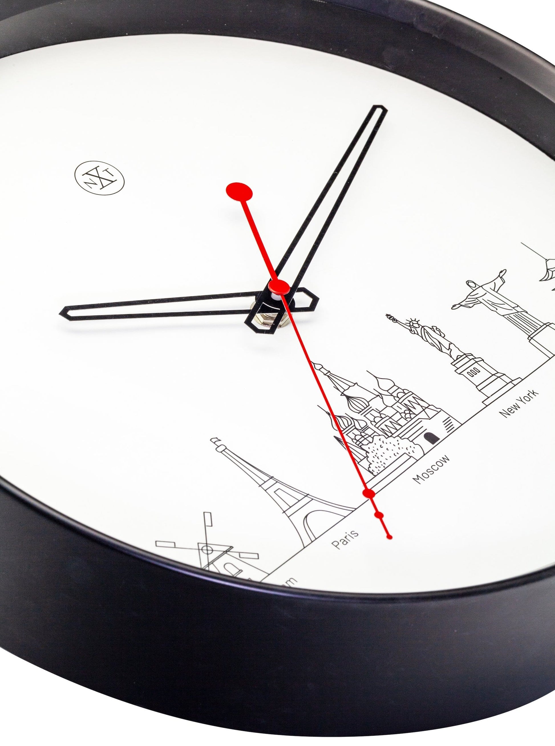 Een minimalistische wandklok met zwart kader en witte wijzerplaat, voorzien van zwart en rood wijzers en iconen van wereldstadjes zoals Amsterdam, Parijs en Tokio. Ideaal voor een moderne, reisgeïnspireerde interieurdecoratie.