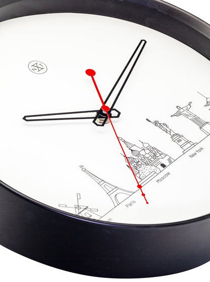 Een minimalistische wandklok met zwart kader en witte wijzerplaat, voorzien van zwart en rood wijzers en iconen van wereldstadjes zoals Amsterdam, Parijs en Tokio. Ideaal voor een moderne, reisgeïnspireerde interieurdecoratie.