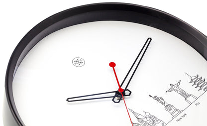 Een moderne wandklok met zwart kader en witte wijzerplaat, waarop gestileerde wereldstad-iconen zijn afgebeeld. Rode wijzers en een minimalistisch ontwerp maken deze klok ideaal voor een wereldreis- of reisgezinsinterieur.