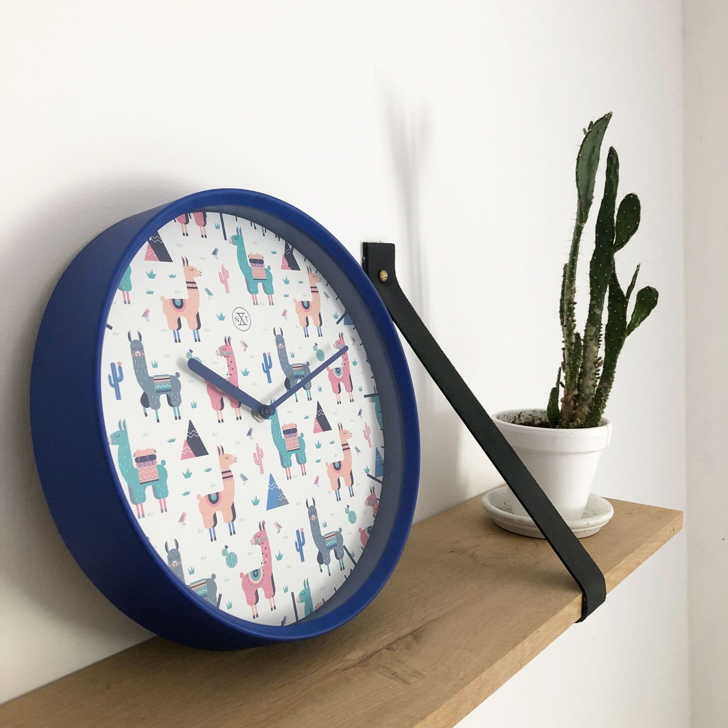 Een ronde wandklok met blauwe rand en kleurrijke alpaca-illustraties op witte achtergrond, perfect voor kinderkamer of speelruimte. Decoratieve klok met thema Andes en cactus, ideaal voor kinderinterieur.